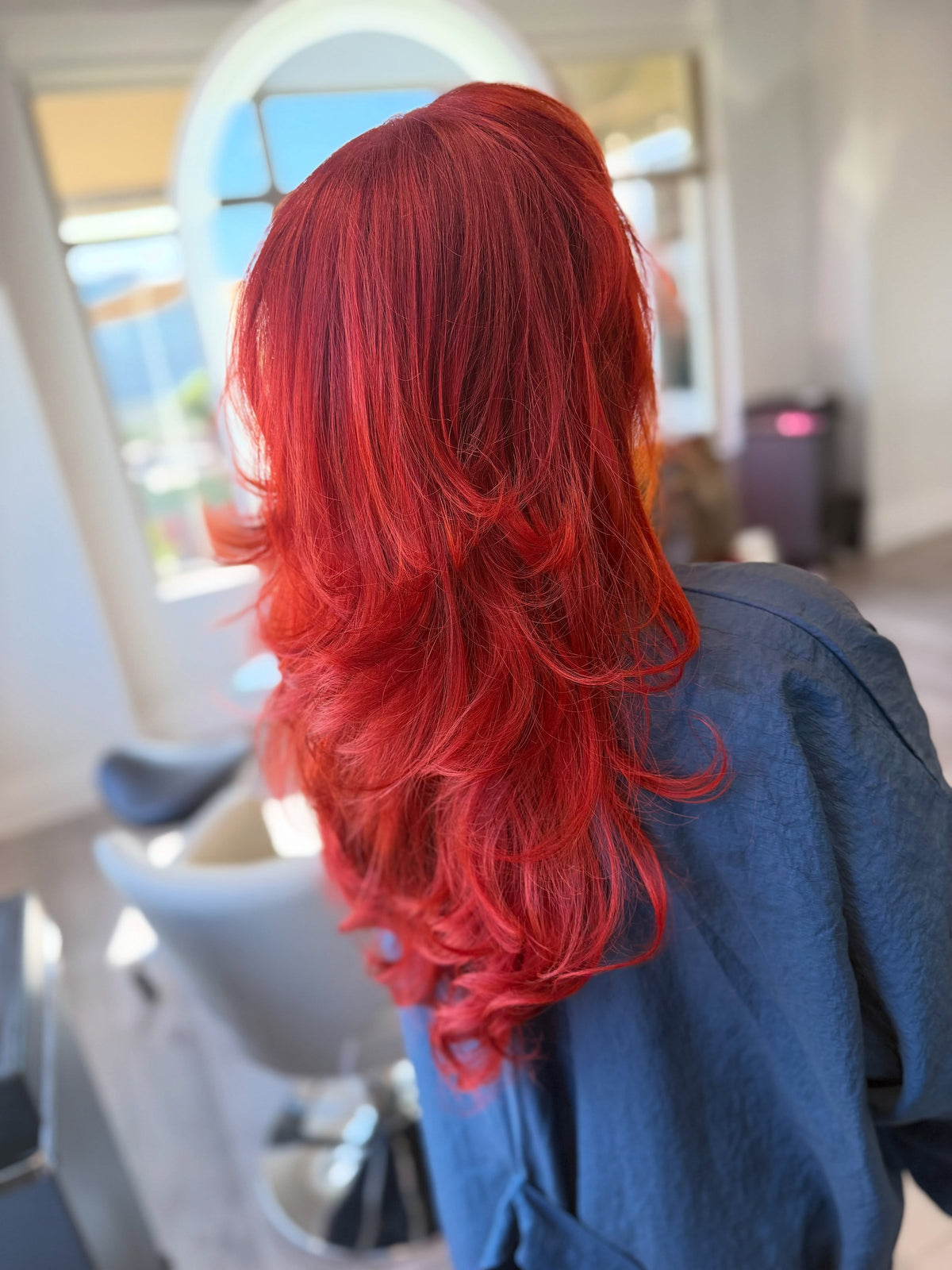 Bright red hair color with face-framing layers by Sam at Salon Sora, Boca Raton